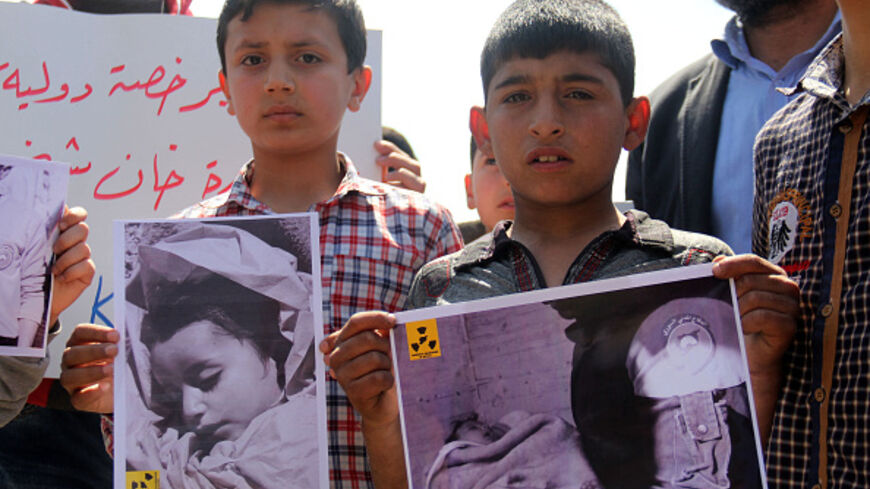 Syrian residents of Khan Sheikhun hold placards on April 7, 2017 during a protest condemning a suspected chemical weapons attack on their town. (OMAR HAJ KADOUR/AFP via Getty Images)