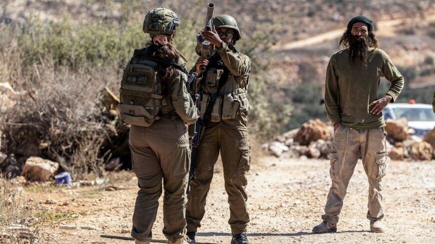 Israeli soldiers and an Israeli settler gather on a road close to an olive grove following a reported attack by settlers on a Palestinian home in the Israeli-occupied West Bank village of Turmus Ayya