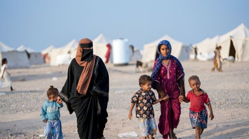 FILE PHOTO: Women and children walk at camp for internally displaced people near Aden