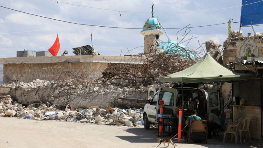 People sit near rubble in Zawtar al-Gharbiyeh