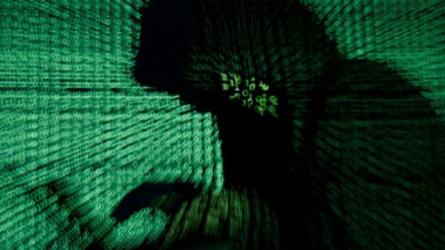 FILE PHOTO: Man holds laptop computer as cyber code is projected on him in this illustration picture