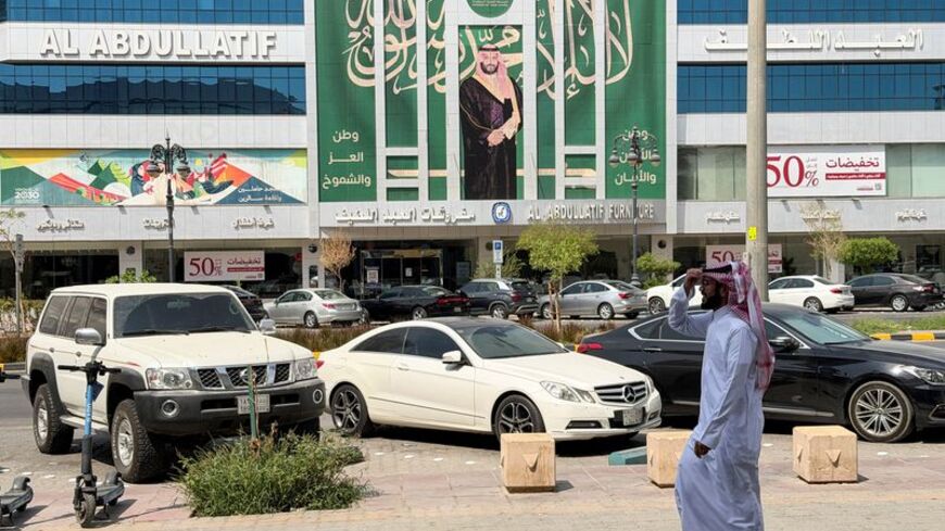A Saudi man walks past a banner of Saudi Crown Prince Mohammed bin Salman displayed on a commercial building in Riyadh