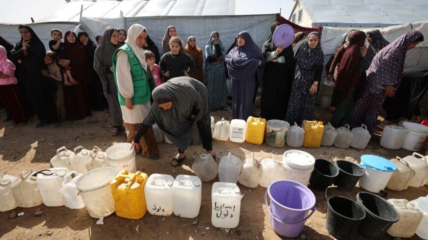 Palestinians displaced during the two-year Israeli offensive wait to fill water containers in Gaza