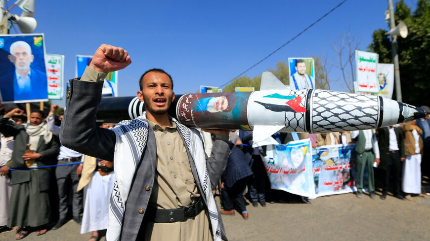 A Yemeni man holds up a mock missile decorated with the colors of the Palestinian flag and the chechered keffiyeh in front of portraits of slain Hamas leader Yahya Sinwar (L) and the leader of the Houthi movement, Abdel Malek al-Houthi (R), during a protest in Sanaa to denounce strikes on Yemen and Israel's bombardment of Gaza on Jan. 15, 2025. 