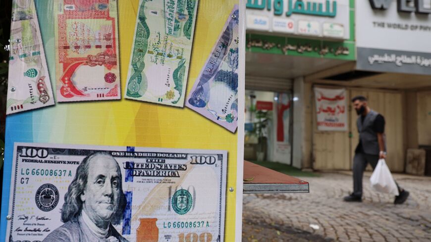 A man walks past a closed foreign exchange office in Baghdad on October 7, 2026. Iraq's central bank devalued the dinar currency against the dollar on October 7, with the country facing a deepening crisis brought on by the Middle East war. (Photo by AHMAD AL-RUBAYE / AFP via Getty Images)