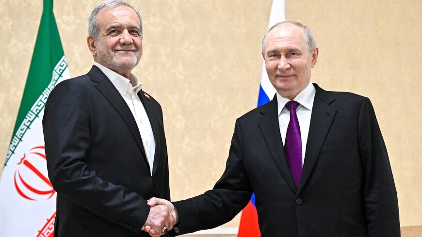 In this pool photograph distributed by the Russian state agency Sputnik, Russia's President Vladimir Putin and Iranian President Masoud Pezeshkian shake hands during a meeting in Turkmenbashi on Oct. 8, 2026.