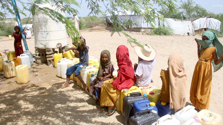 Internally displaced Yemenis queue at a water tank dispenser