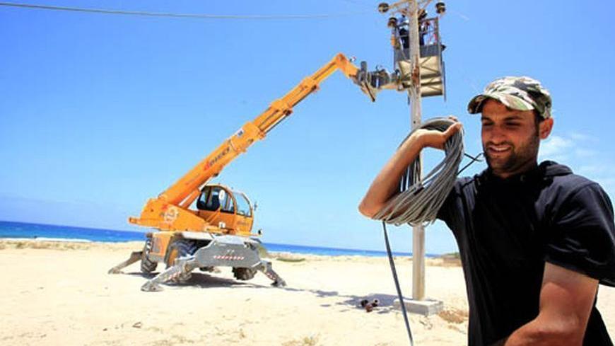 Workers repair electricity lines on the road from the Libyan rebel-held city of Misrata to the western frontline, where rebels trying to advance on the capital Tripoli are fighting forces loyal to Muammar Gaddafi, June 20, 2011. REUTERS/Zohra Bensemra (LIBYA - Tags: CONFLICT ENERGY)