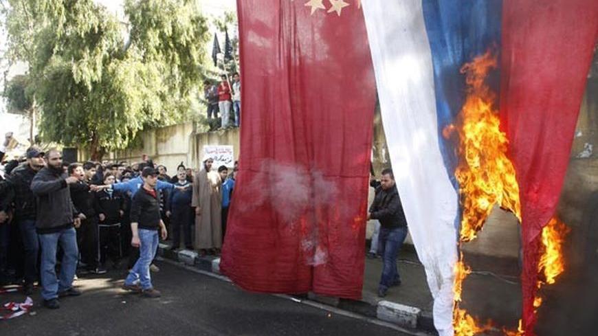 Protesters burn Chinese and Russian flags during a protest organized by Sunni Islamists group at Sidon, southern Lebanon, against the vetoing by Russia and China of a U.N. resolution that backed an Arab plan calling on Syrian President Bashar al-Assad to quit, and to express solidarity with Syria's anti-government protesters, February 10, 2012. REUTERS/Ali Hashisho  (LEBANON - Tags: POLITICS CIVIL UNREST)