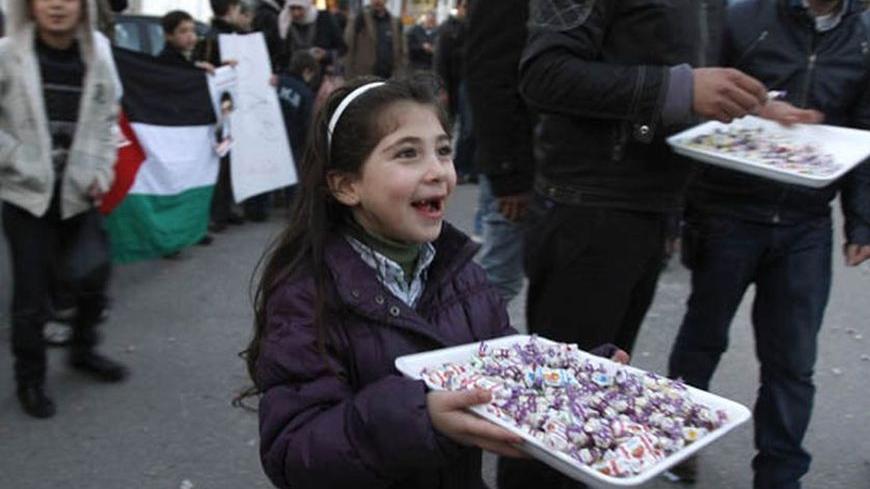 A Palestinian girl hands out candies to passers-by in the West Bank city of Ramallah February 21, 2012 to celebrate the upcoming release of Islamic Jihad member Khader Adnan. Adnan, held without trial by Israel, agreed on Tuesday to end his 66-day hunger strike after Israeli authorities promised to release him in April in a deal that avoided judicial review of the detention policy. REUTERS/Mohamad Torokman (WEST BANK - Tags: POLITICS SOCIETY)