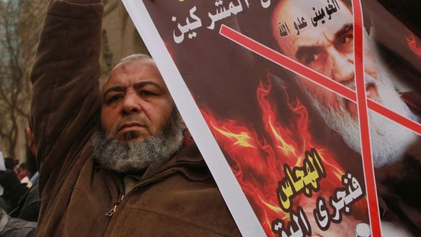 A demonstrator holds a crossed out poster depicting Iran's late leader Ayatollah Khomeini during a protest against Syria's President Bashar al-Assad, near the Syrian embassy in Cairo February 17, 2012. The Arab writings on the poster read "God protects the Muslims in Syria. Khomeini is the enemy of God."    REUTER/Mohammed Salem (EGYPT - Tags: POLITICS CIVIL UNREST)