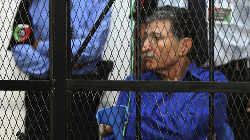 Former spy chief in Muammar Gaddafi's government, Bouzaid Dorda, sits behind bars in the dock during a court session in Tripoli June 26, 2012. Dorda, who was arrested last September in Tripoli, is the first senior Gaddafi official put on trial in Libya since a popular revolution ousted the former government last year. REUTERS/Ismail Zitouny (LIBYA - Tags: POLITICS CIVIL UNREST CRIME LAW)