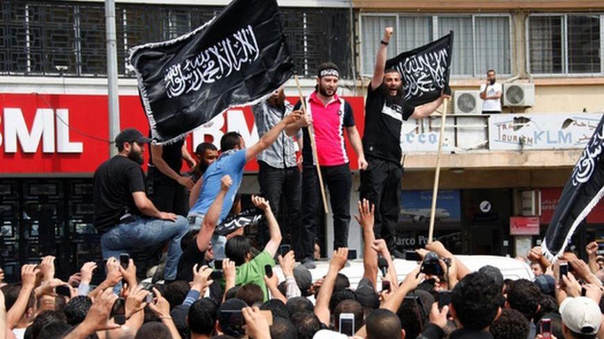 Sunni Islamist and anti-Syrian regime activist Shadi al-Moulawi (2nd R) stands on a top of a van as he carries a flag and is welcomed by a crowd shouting slogans, gesturing and filming him in Tripoli, northern Lebanon May 22, 2012. A court on Tuesday released on bail al-Moulawi, whose arrest earlier this month set off violent clashes in northern Lebanon that killed at least eight people. The flag reads: "There is no god but Allah, Muhammad is Allah's messenger". REUTERS/Omar Ibrahim   (LEBANON - Tags: POLIT