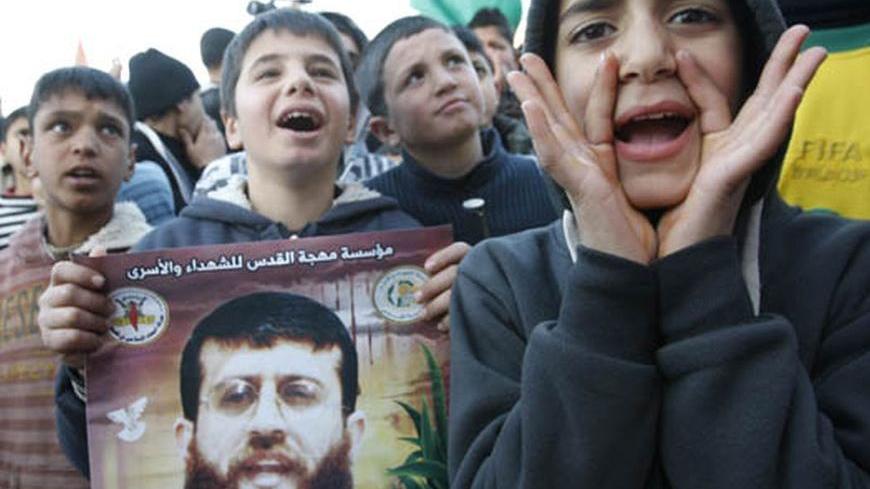 A Palestinian boy holds a poster with an image of Islamic Jihad member Khader Adnan during a news conference announcing his upcoming release outside Adnan's home in the West Bank village of Arabeh, near Jenin February 21, 2012. Adnan, held without trial by Israel, agreed on Tuesday to end his 66-day hunger strike after Israeli authorities promised to release him in April in a deal that avoided judicial review of the detention policy. REUTERS/Abed Omar Qusini (WEST BANK - Tags: POLITICS CIVIL UNREST)
