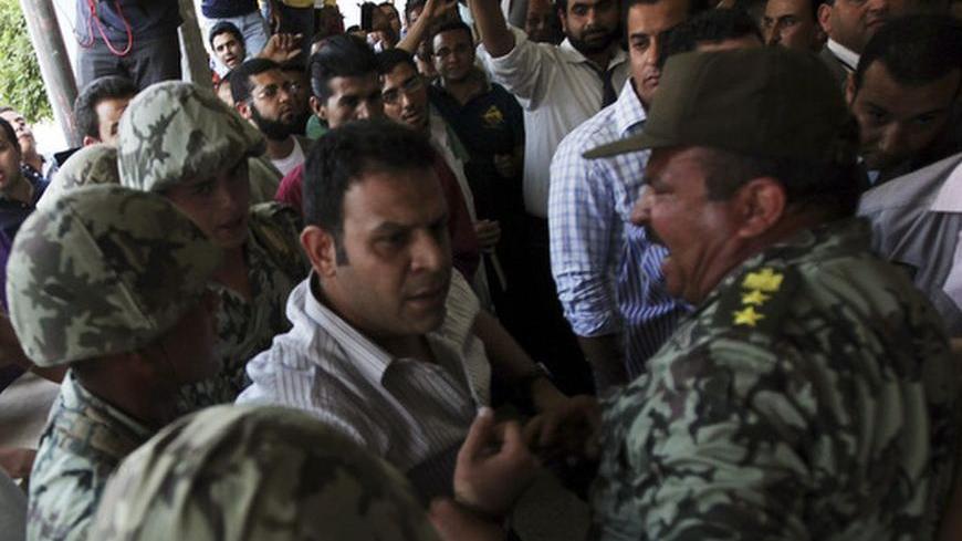 Army soldiers hold back a protester who tried to attack former prime minister and presidential candidate Ahmed Shafiq as he is leaving a polling station, after casting his vote in Cairo May 23, 2012. Protesters threw stones and shoes at Egyptian presidential candidate Shafiq after he cast his ballot on Wednesday, taking aim at the former prime minister for serving under deposed leader Hosni Mubarak. REUTERS/Amr Abdallah Dalsh  (EGYPT - Tags: POLITICS CIVIL UNREST ELECTIONS MILITARY)
