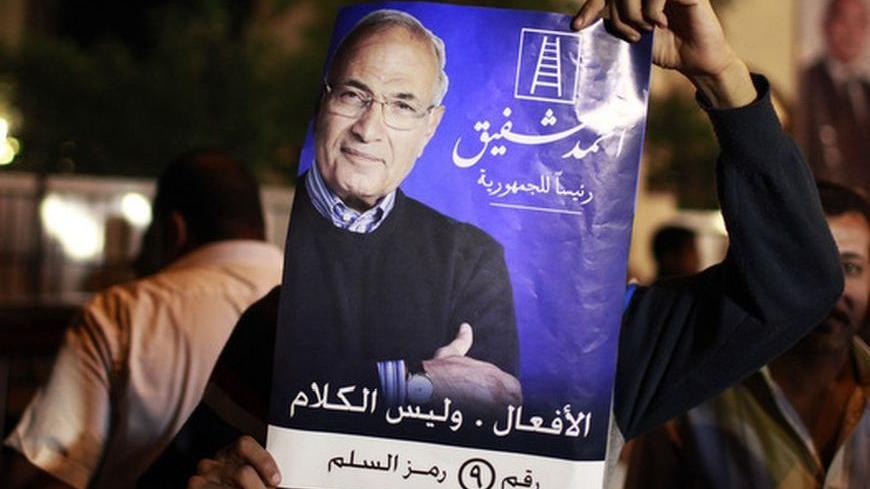 A supporter of candidate Ahmed Shafiq holds his picture as he celebrates in Cairo May 25, 2012. The prospect of Shafiq succeeding Hosni Mubarak as president of Egypt is a nightmare for revolutionaries and Islamists, but a security blanket for those wary of change. REUTERS/Suhaib Salem (EGYPT - Tags: POLITICS CIVIL UNREST)