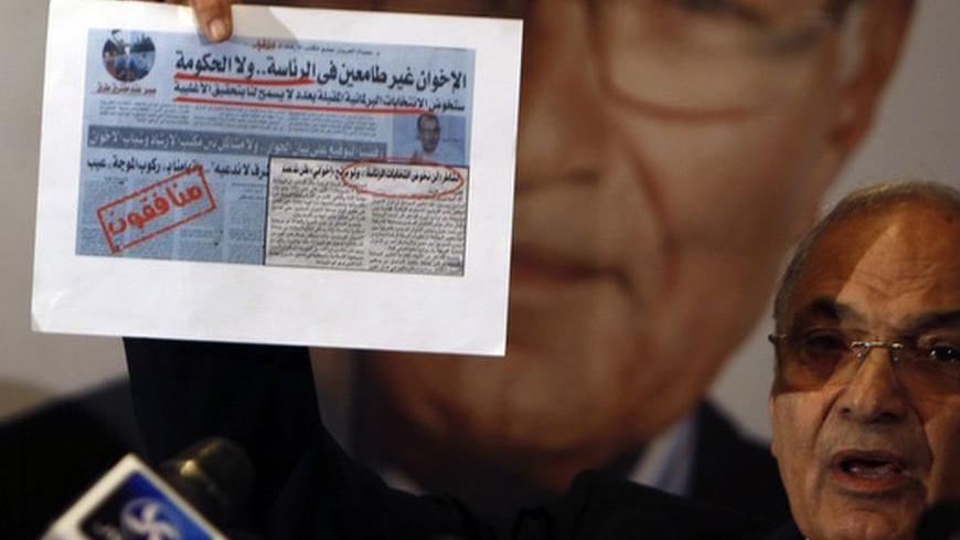Former Prime Minister and current presidential candidate Ahmed Shafiq shows an old newspaper article, in which the Muslim Brotherhood said they were not interested in the presidency nor the government, during a news conference in Cairo June 3, 2012. Egyptians living abroad started voting today in the second round of the country?s presidential election, scheduled for June 16-17. REUTERS/Amr Abdallah Dalsh  (EGYPT - Tags: POLITICS ELECTIONS)