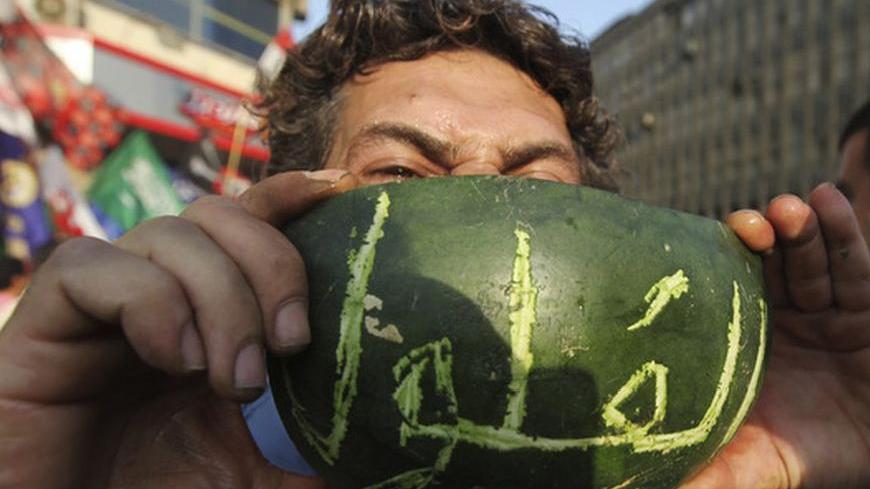 A man eats water melon carved with the word "Feloul", as supporters of the Muslim Brotherhood's presidential candidate Mohamed Morsy celebrate and shout anti military counciel at Tahrir square in Cairo June 19, 2012. Egypt's Muslim Brotherhood declared on Tuesday it did not want a confrontation with the ruling generals but said the army did not have the right to curb presidential powers after a vote the group says its candidate won. "Feloul" is a pejorative Egyptian political slang used to refer to "remnant