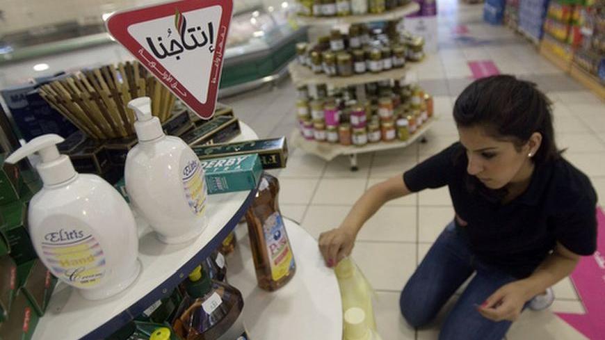 A Palestinian worker sticks Intajuna ("Our Products") stickers on Palestinian goods displayed in a supermarket in the West Bank city of Ramallah August 2, 2009. Intajuna is one of many campaigns asking Palestinians to avoid Israeli products. After 40 years of occupation, the Palestinian economy is tied to Israel's, so attempts to reduce its dependence clash with hard realities. Picture taken August 2, 2009. To match feature PALESTINIANS-ISRAEL/BOYCOTT REUTERS/Fadi Arouri (WEST BANK POLITICS BUSINESS)