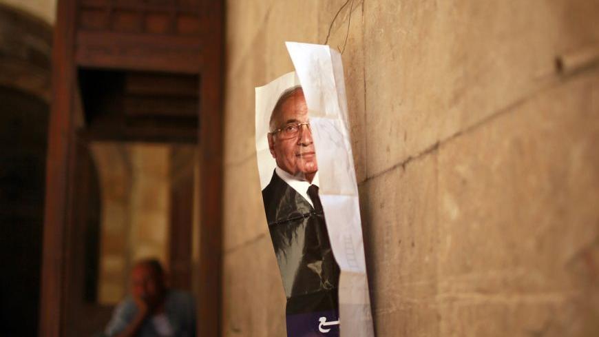 A man sits outside a shop as a poster of presidential candidate Ahmed Shafiq is seen hanging on a wall in Cairo June 13, 2012. The Brotherhood's Mohamed Mursi will face Shafiq, the last prime minister of ousted leader Hosni Mubarak, in a presidential run-off on June 16 and 17, the climax of Egypt's first free leadership contest after 16 months of military rule. REUTERS/Suhaib Salem (EGYPT - Tags: POLITICS CIVIL UNREST)