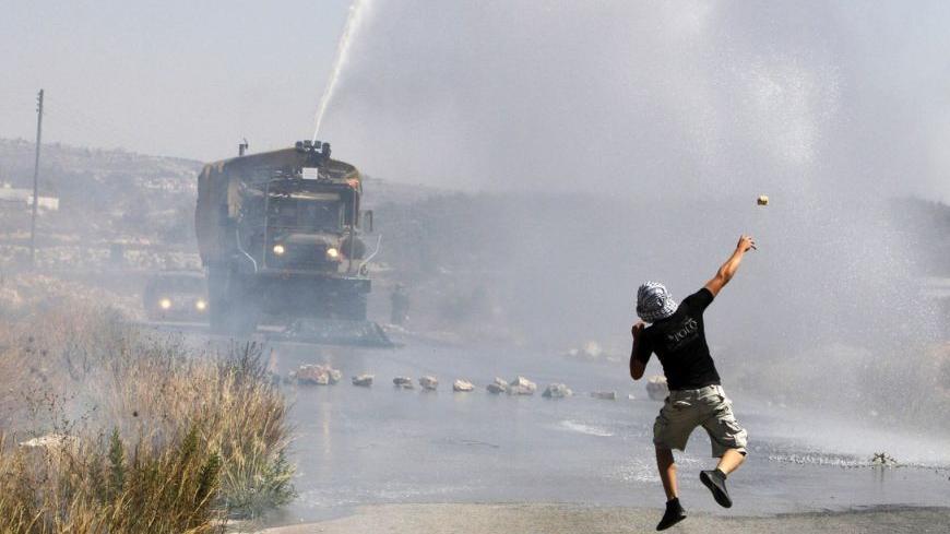 A Palestinian demonstrator hurls a stone as an Israeli truck fires a water cannon containing a foul smelling substance during clashes at a protest in the West Bank village of Nabi Saleh, near Ramallah September 14, 2012. The demonstrators were calling for an end to the Oslo accords, which were meant to pave the way to permanent peace with Israel. REUTERS/Mohamad Torokman (WEST BANK - Tags: POLITICS CIVIL UNREST)