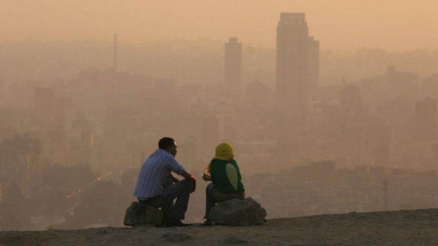 An Egyptian couple chat at the top of a mountain area that looks over Cairo during a smoggy day July 12, 2008  REUTERS/Asmaa Waguih   (EGYPT)