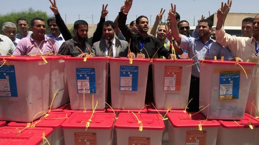 High Election Commission workers chant the national anthem behind ballot boxes which just arrived from the region of Kufra, five days after Saturday's landmark national elections, at the High Election Commission Center in Tripoli July 12, 2012. Voting in Kufra was held up by security problems in the area, with anti-poll protesters attacking election facilities. Libyans, relieved that their first free national election in 60 years had survived violence and protests, celebrated the chance to draw a line under