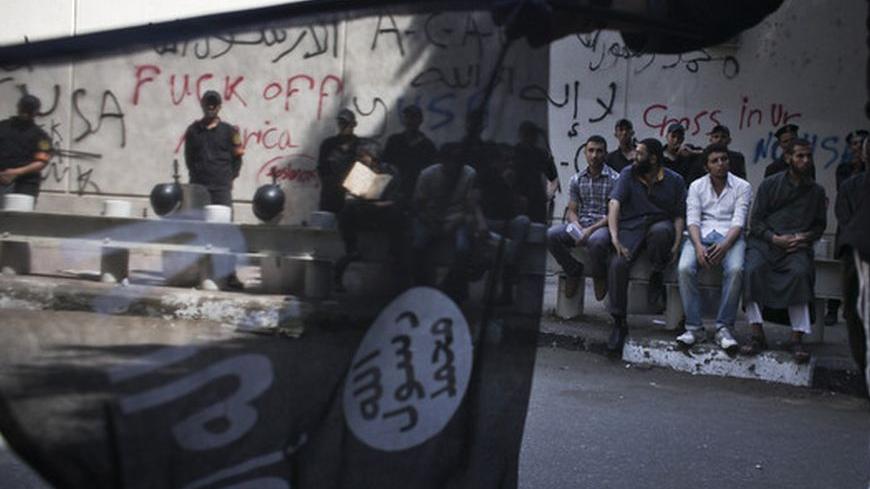 An Egyptian flag seller waves an Islamist flag in front of riot police and protesters outside of the graffitied US embassy in downtown Cairo, Egypt, Wednesday, Sept 12, 2012. (Photo by Tara Todras-Whitehill)