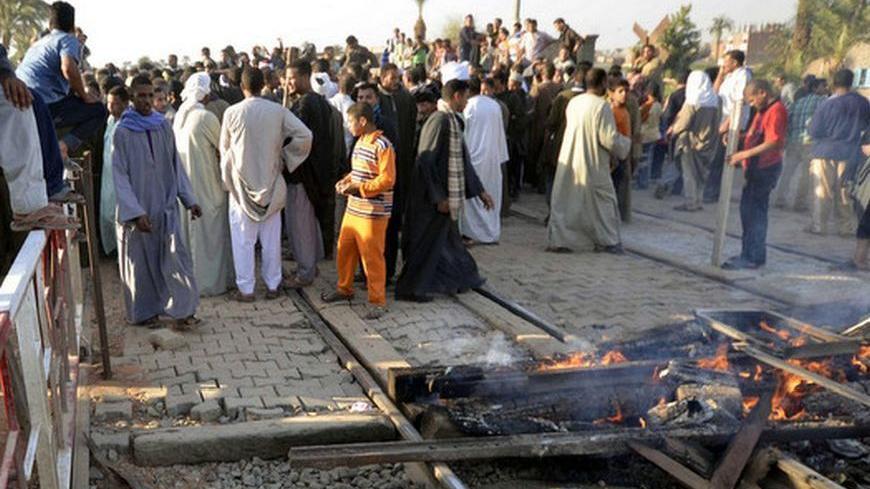 People gather at the site of a train crash in the city of Manfalut near Assiut, about 300 km (186 miles) south of Cairo, November 17, 2012. Fifty people, mostly children, were killed when a train slammed into a school bus as it crossed the tracks at a rail crossing south of Cairo on Saturday, further inflaming public anger at Egypt's shoddy transport network. REUTERS/Stringer (EGYPT - Tags: DISASTER TRANSPORT)