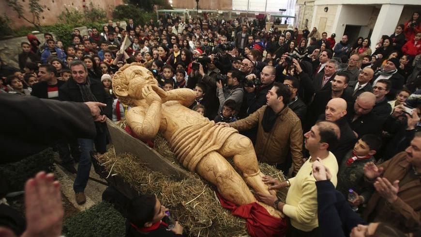 Palestinians surround a cart carrying a wooden statue of baby Jesus before a march in the West Bank town of Bethlehem December 20, 2012, ahead of Christmas. REUTERS/Mohamad Torokman (WEST BANK - Tags: RELIGION TPX IMAGES OF THE DAY)