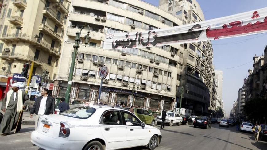 People and vehicles travel under a banner which reads "People isolate President", at Tahrir Square, after protesters opened it to traffic, in Cairo December 30, 2012. Egyptian Prime Minister Hisham Kandil said on Sunday he expected a resumption of talks in January with the International Monetary Fund on a $4.8 billion loan. REUTERS/Amr Abdallah Dalsh  (EGYPT - Tags: POLITICS CIVIL UNREST)