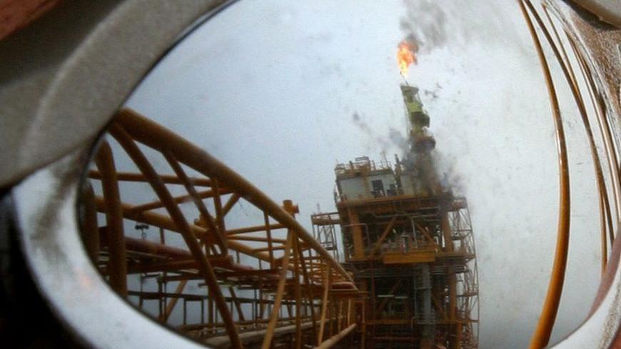 An oil production platform is reflected on the sunglasses of an Iranian worker at the Soroush oil fields in the Persian Gulf, 1,250 km (776 miles) south of the capital Tehran, July 25, 2005. Picture taken July 25, 2005. REUTERS/Raheb Homavandi  CJF/KS
