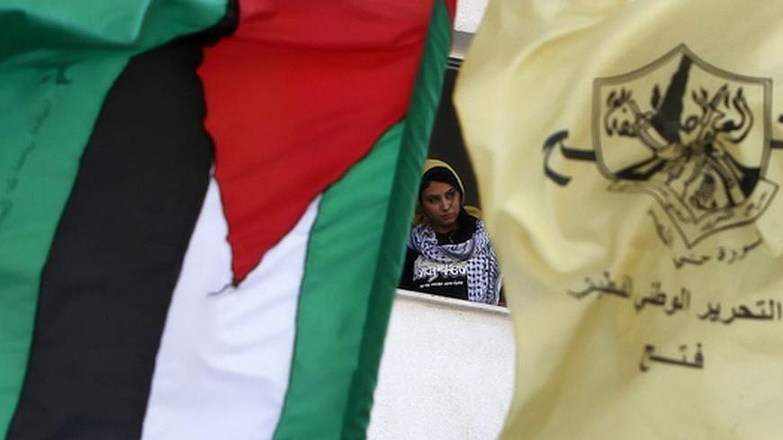 A Palestinian flag flutters next to the Fatah party's yellow flag as a student stands by a window during a rally celebrating the political unity deal between Gaza rulers Hamas and the rival party Fatah at Al-Azhar University in Gaza City on May 8, 2011. AFP PHOTO/MAHMUD HAMS (Photo credit should read MAHMUD HAMS/AFP/Getty Images)