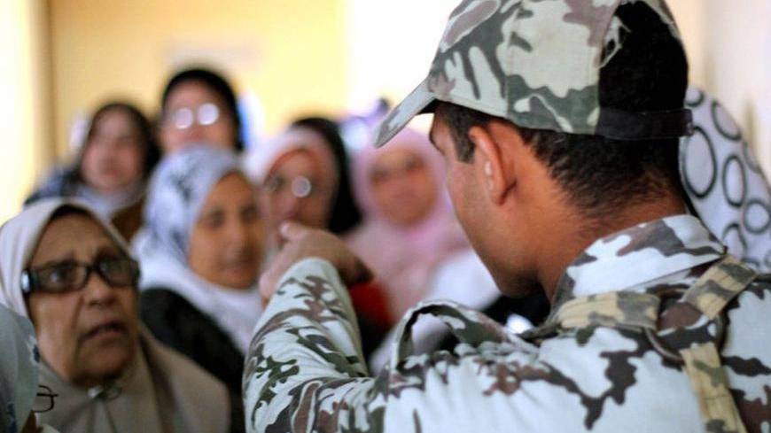 A military soldier directs a line of female voters inside Al-Baheyya Al-Burhameyya polling station in Cairo's poor Sayyeda Zeinab district where hundreds of voters lined around the building to cast their ballots in the first phase of Egypt's nationwide constitutional referendum. Saturday Dec. 15, 2012.