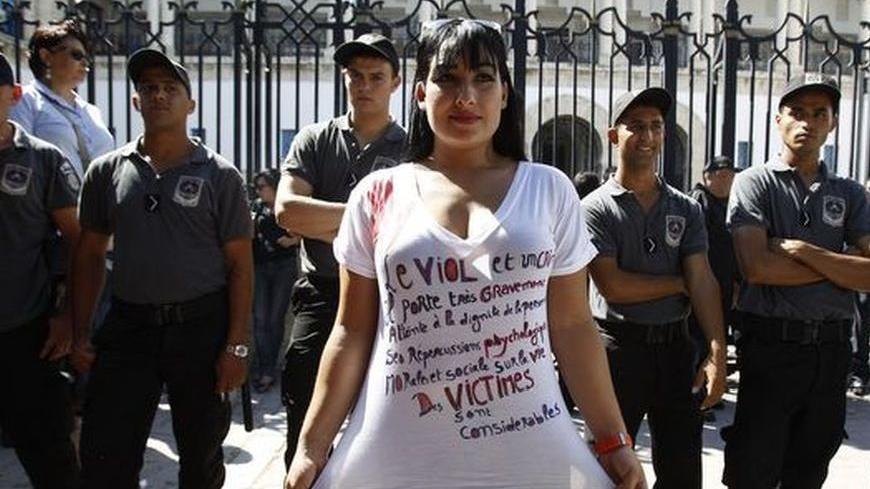 A protester poses in front of police officers during a demonstration against charges of indecency filed against a woman raped by two police officers, in front of the court in Tunis October 2, 2012. Amnesty International has called for the indecency charges against the woman, who prefers to remain anonymous, filed by the same two police officers found guilty and jailed for raping her, to be dropped.   REUTERS/Zoubeir Souissi   (TUNISIA - Tags: POLITICS CIVIL UNREST CRIME LAW)