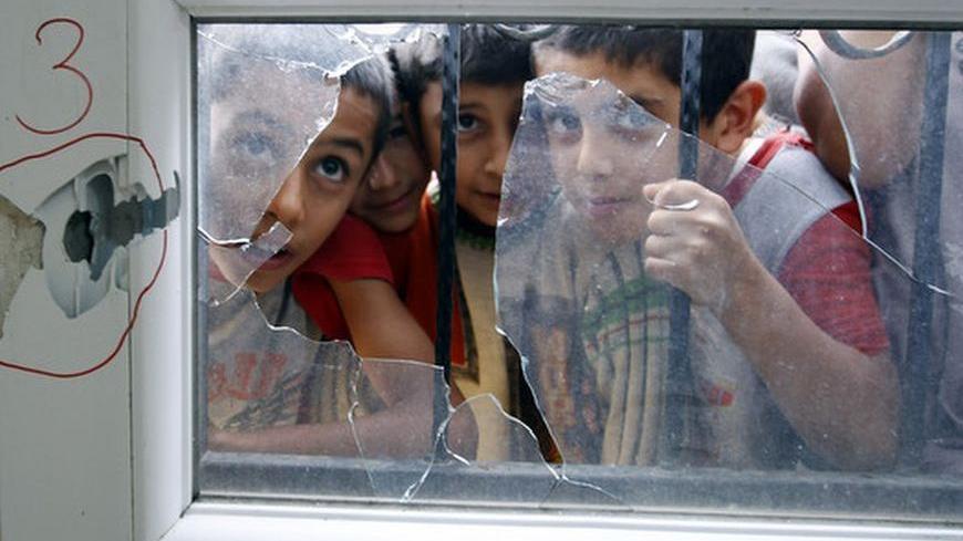 Turkish boys look through a shattered window after an anti-aircraft shell fired from Syria hit a health centre across the border in the Reyhanli district of Turkey's Hatay province October 23, 2012. REUTERS/Osman Orsal (TURKEY - Tags: POLITICS CIVIL UNREST HEALTH SOCIETY TPX IMAGES OF THE DAY)