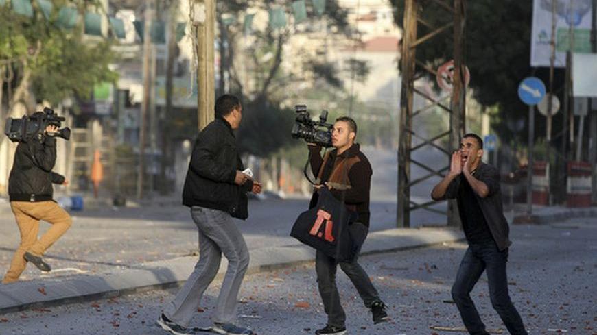 Palestinian journalists react after an Israeli air strike on the office of Hamas television channel Al-Aqsa in a building that also houses other media in Gaza City November 18, 2012. Israel bombed militant targets in Gaza for a fifth straight day on Sunday, launching aerial and naval attacks as its military prepared for a possible ground invasion, though Egypt saw "some indications" of a truce ahead.  REUTERS/Majdi Fathi (GAZA - Tags: MILITARY CONFLICT MEDIA)