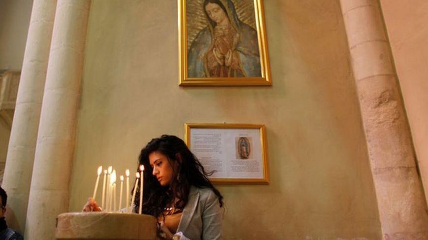 A Palestinian Christian lights a candle during a prayer to show solidarity with Gaza, at a Catholic church in the West Bank town of Beit Jala near Bethlehem November 18, 2012. Israel bombed Palestinian militant targets in the Gaza Strip from air and sea for a fifth straight day on Sunday, preparing for a possible ground invasion while also spelling out its conditions for a truce. REUTERS/Ammar Awad (WEST BANK - Tags: POLITICS CIVIL UNREST RELIGION)
