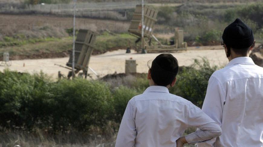 Ultra-Orthodox Jewish youths look at an Iron Dome anti-missile battery near Tel Aviv November 19, 2012. Israel bombed dozens of targets in Gaza on Monday and said that while it was prepared to step up its offensive by sending in troops, it preferred a diplomatic solution that would end Palestinian rocket fire from the enclave. REUTERS/Baz Ratner (ISRAEL - Tags: CIVIL UNREST POLITICS MILITARY)