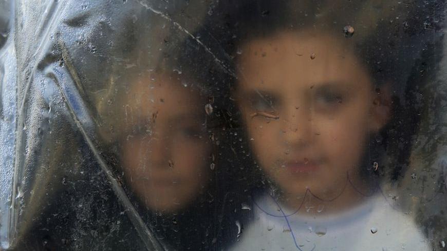 A Syrian refugee girl looks from behind a plastic sheet inside the makeshift tent where she temporarily lives with her family in Bar Elias village in the Bekaa valley December 13, 2012.REUTERS/ Jamal Saidi    (LEBANON - Tags: POLITICS CIVIL UNREST)