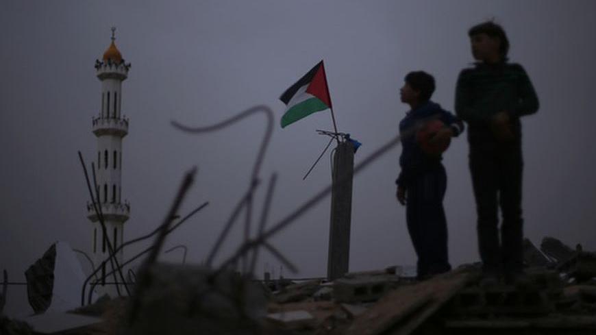 A Palestinian flag flutters as Palestinian boys stand atop the rubble of a house, which witness said was destroyed in an Israeli air strike during an eight-day conflict, in the northern Gaza Strip December 20, 2012. Eight days of Israeli air strikes on Gaza and cross-border Palestinian rocket attacks ended in an Egyptian-brokered truce agreement last month calling on Israel to ease restrictions on the territory. REUTERS/Mohammed Salem (GAZA - Tags: CONFLICT TPX IMAGES OF THE DAY)