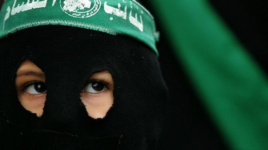 A masked Palestinian boy wears a Hamas banner on his head as he participates in a Hamas rally in Gaza December 23, 2005. Thousands of Hamas members marched in Gaza City on Friday to condemn the [United States and Europe and to demand that President Mahmoud Abbas] not delay the upcoming parliament vote.