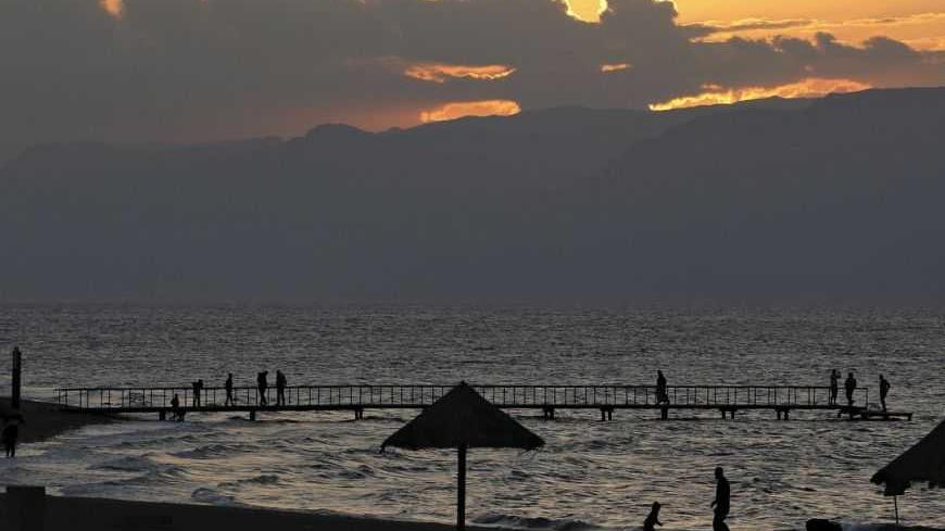 People are seen as the sun sets over a beach in the Aqaba Gulf on the Red Sea, south of Amman November 25, 2011. Picture taken November 25, 2011. REUTERS/Muhammad Hamed (JORDAN - Tags: SOCIETY)