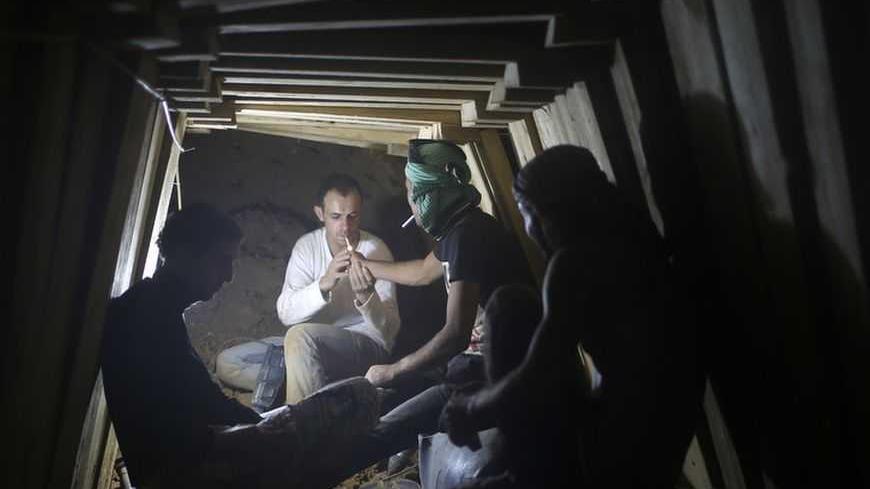 Palestinians smoke cigarettes as they work inside a smuggling tunnel dug beneath the Egyptian-Gaza border in Rafah, in the southern Gaza Strip November 26, 2012. Knee-deep in craters carved out by Israeli air strikes, Palestinians wielded shovels and planks to reopen tunnels used to smuggle in goods from Egypt to Gaza, as international aid agencies raced to replenish Gaza's supplies. REUTERS/Mohammed Salem (GAZA - Tags: CONFLICT) - RTR3AWAH