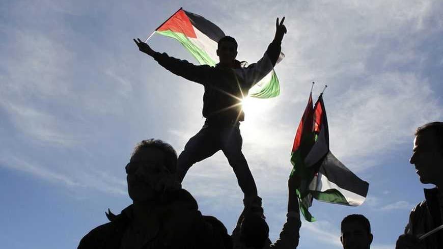 Palestinians wave flags during a rally marking the U.N. General Assembly's upgrading of the Palestinians' status from "observer entity" to "non-member state", in the West Bank city of Ramallah December 2, 2012. Israel said on Sunday it was withholding this month's transfer of tax revenues to the Palestinian Authority, after the United Nations' de facto recognition of a Palestinian state.  REUTERS/Ammar Awad (WEST BANK - Tags: POLITICS CIVIL UNREST TPX IMAGES OF THE DAY)