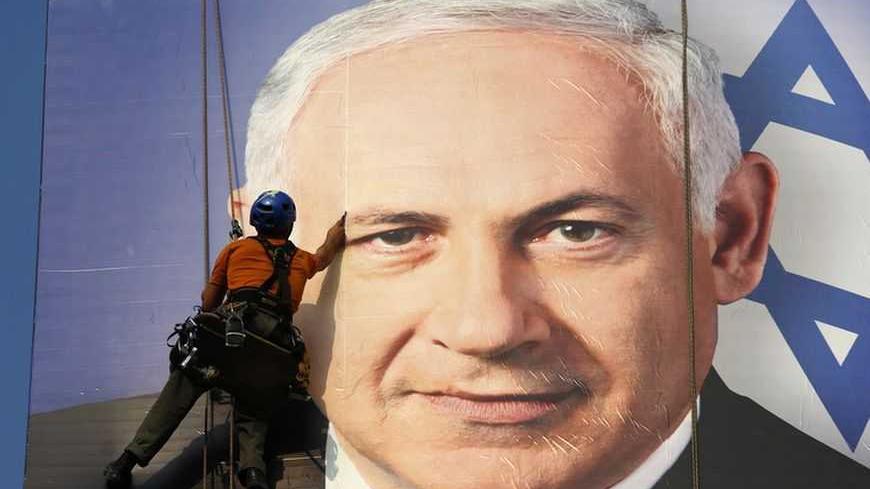 A worker installs a banner depicting Israel's Prime Minister Benjamin Netanyahu in Tel Aviv January 17, 2013. Netanyahu looks set to form a new governing coalition after next week's election, polls show, with the only question being whether he wants to soften its hardline contours. REUTERS/Baz Ratner (ISRAEL - Tags: POLITICS ELECTIONS TPX IMAGES OF THE DAY)