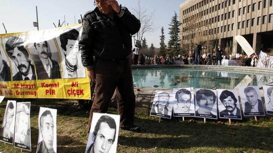 A man looks at portraits of people who were executed, disappeared or died in jail during military rule after a 1980 coup, as protesters demonstrate in front of a courthouse in Ankara April 4, 2012. Thousands of mainly leftist protesters gathered outside the court, waving flags and shouting slogans demanding justice and the prosecution of more than just the coup ring-leaders. More than 30 years after the September 12, 1980 military takeover, an Ankara court began hearing the case against 94-year-old Retired 
