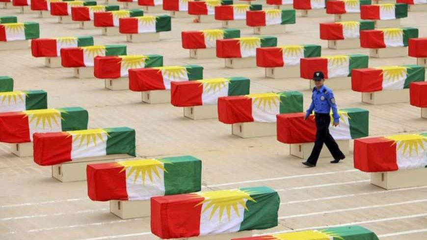 An Iraqi policeman of Kurdish descent walks between coffins draped with Kurdish flags containing the remains of victims during a burial ceremony in Sulaimaniya, 260km (162 miles) northeast of Baghdad, May 28, 2012. More than 700 Kurds, killed by former Iraqi leader Saddam Hussein, were honoured in a ceremony in northern Iraq on Monday. Kurdish officials gathered at the Police Academy in Suleimaniya province to mourn 730 victims of Iraq's notorious 'Anfal' campaign, whose bodies were discovered in mass grave