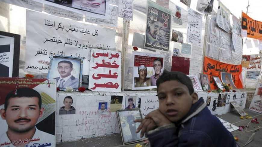 Mahmoud, 9, sits in front of a "Revolution Museum", dedicated to protesters killed during Egypt's uprising, set up by protesters against Egypt's President Mohamed Mursi at Tahrir Square in Cairo December 17, 2012. Egypt's opposition called for nationwide protests against a constitution backed by Mursi, after a vote exposed deep divisions that could undermine his efforts to build consensus for tough economic measures. REUTERS/Amr Abdallah Dalsh (EGYPT - Tags: POLITICS CIVIL UNREST)