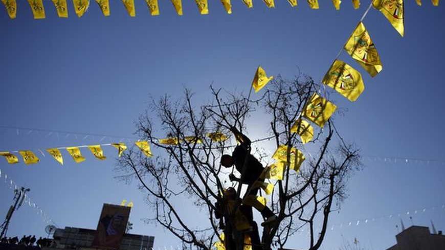 Palestinian youths are silhouetted as they hang a string of Fatah flags during a rally marking the 48th anniversary of the founding of the Fatah movement in the West Bank town of Bethlehem December 31, 2012. REUTERS/Ammar Awad (WEST BANK - Tags: POLITICS ANNIVERSARY CIVIL UNREST TPX IMAGES OF THE DAY)